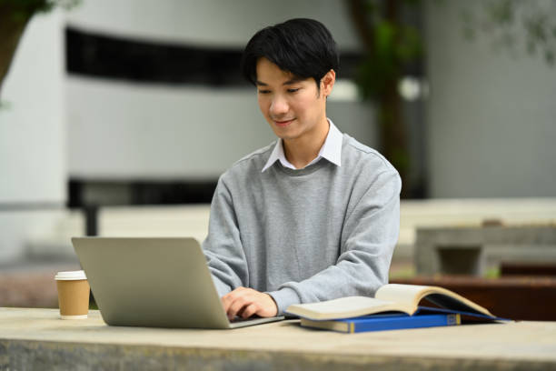 istock Happy asian student man typing on laptop, searching information, surfing the internet while sitting at park table 1712923823