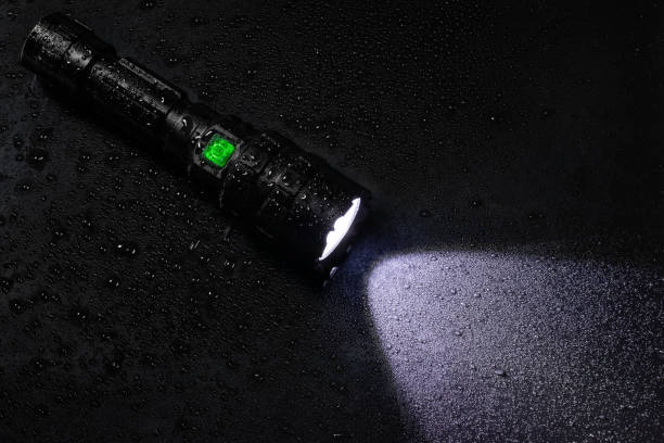 istock Tactical waterproof flashlight with waterdrops on black background 1712923857
