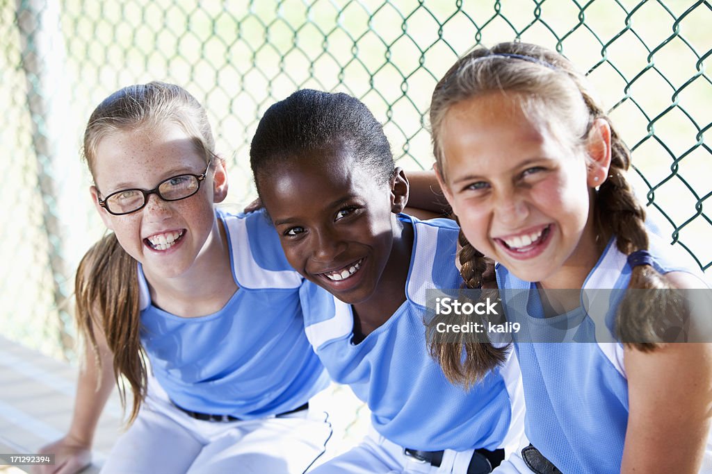 Girls softball équipe assis dans le banc de touche - Photo de Petites filles libre de droits
