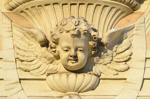 Small child with wings depicted as an angel on a facade decoration