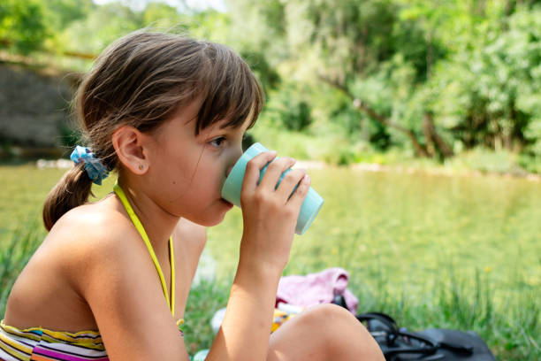 istock Girl drinking water from plastic cup at riverbank 1712925399