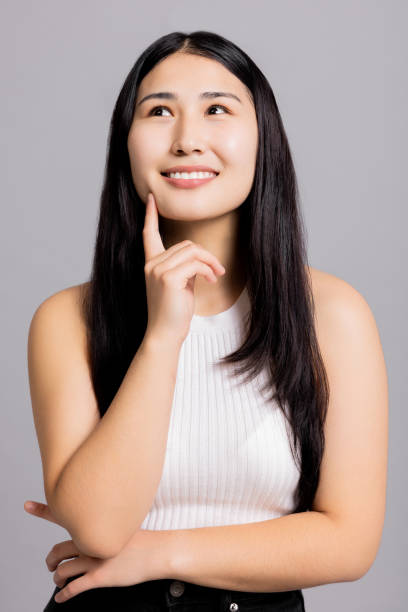 istock Inquisitive curious asian young adorable girl thinking having an idea looking up on grey background copyspace 1712927021