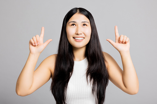 Portrait of adorable delighetd woman pointing index finger herself impressed she choose news wear good look white asic casua t-shirt isolated over grey background looking up curiously.