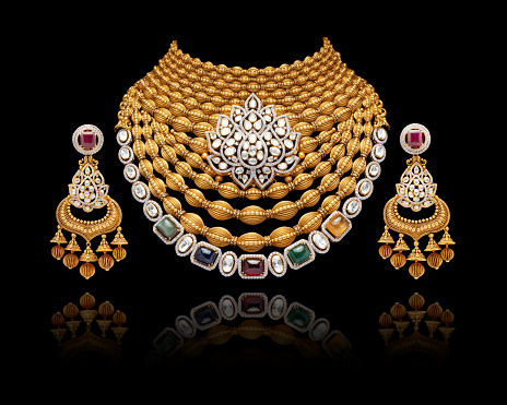 Close-up of gold and diamond necklace with earrings on black background.