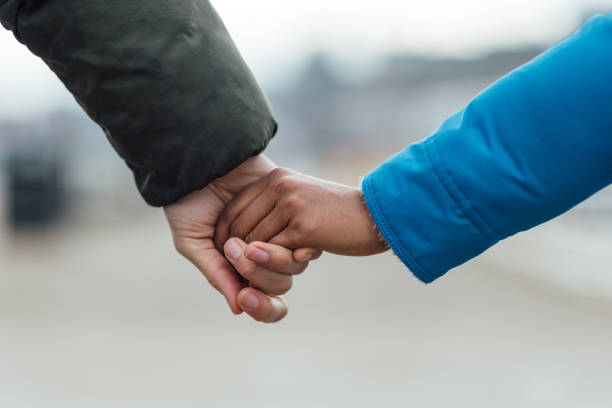 A close-up shot of an unrecognisable couple holding hands in the seaside town of Whitby.Video is also available for this scenario.