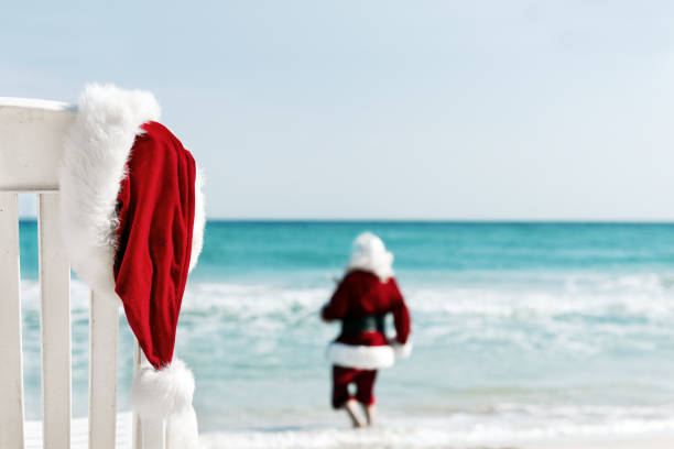 Christmas Santa Claus hat with sun lounger on beautiful tropical summer beach at sunset, calibration on summer holiday vacation at tropical island.