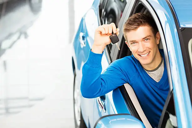 Portrait of a handsome young man holding car key. Horizontal shot.