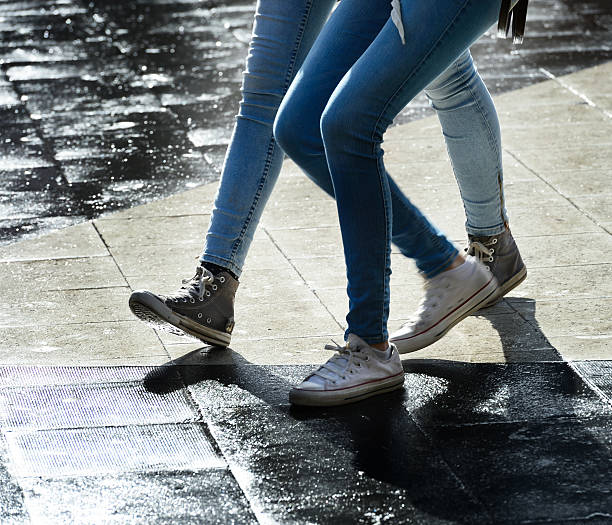 Women on rain wet square Women crossing tiled square after rain. stockholm town square sergels torg sweden stock pictures, royalty-free photos & images