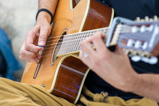 Close up of a person playing an acoustic guitar outdoors. Selective focus