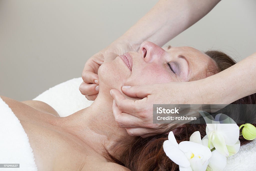 Mature Woman having relaxing massage Mature Woman having relaxing head and face massage Massaging Stock Photo