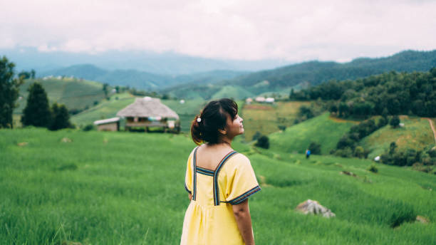 la femme de la tribu montagnarde à ban pa bong piang, province de chiangmai, thaïlande. profitant dans une rizière, la tribu montagnarde non identifiée courait avec des vêtements traditionnels. la femme se sent relaxante et profite dans la prairie et  - asian tribal culture photos photos et images de collection