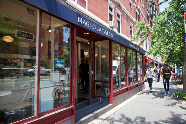 New York City "New York City, USA - June 8, 2012: The shop of Magnolia Bakery at Columbus Avenue in Upper West Side Manhattan. Magnolia Bakery is famous for its various cupcakes and desserts. In the background people walk along the shop." magnolia bakery stock pictures, royalty-free photos & images