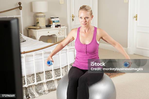 Photo libre de droit de Femme Faisant De Lexercice Tout En Regardant Un Dvd Sur La Télévision De Remise En Forme banque d'images et plus d'images libres de droit de Adulte