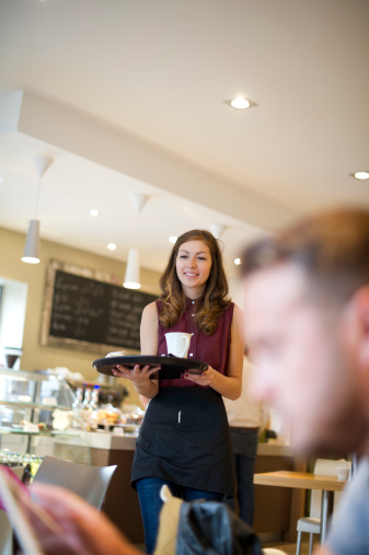 young waitress carrying cake and coffee in a cafe