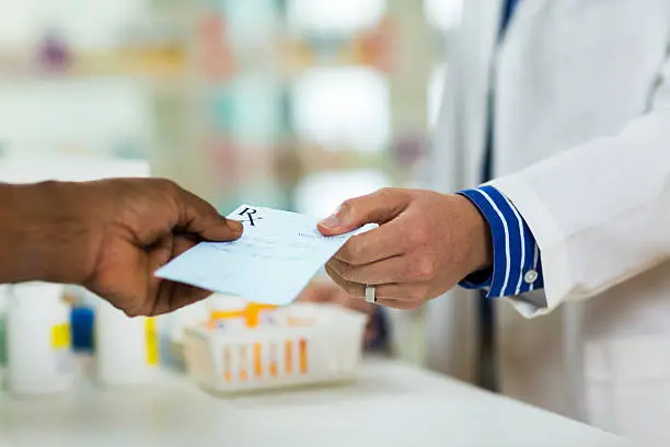 A man handing a prescription to a pharmacists