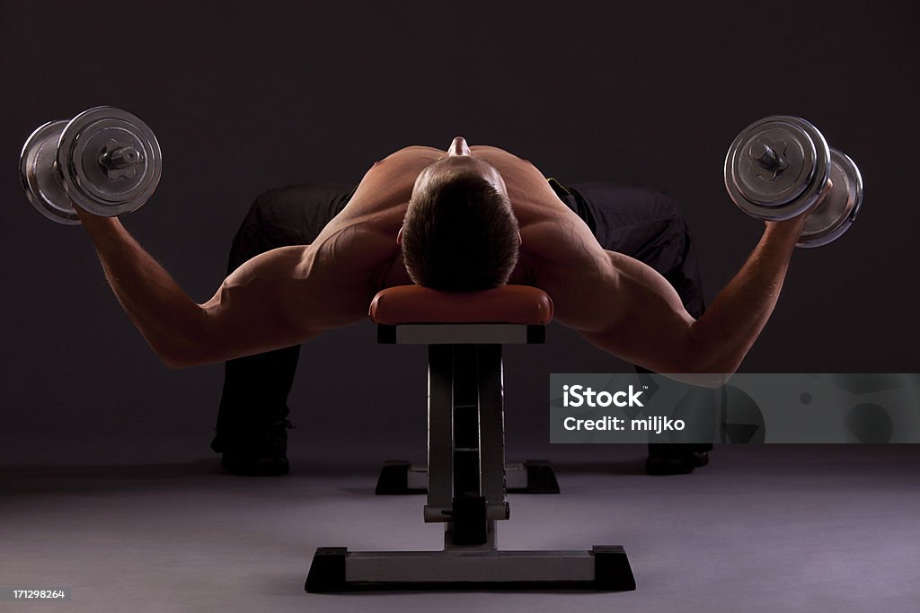 Bodybuilder exercício com halteres no banco - Foto de stock de Academia de ginástica royalty-free