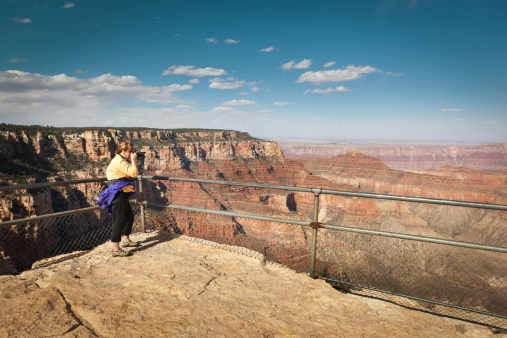 Subject: A woman tourist taking pictures of the Grand Canyon at Cape Royal in the North Rim of Grand Canyon National Park.