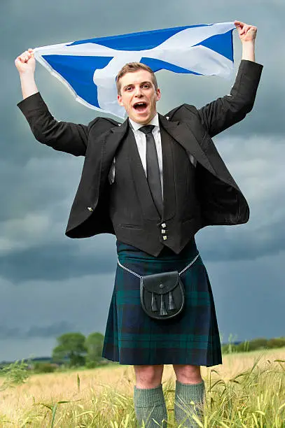 Scotsman in kilt waving flag and shouting for ScotlandMore like this
