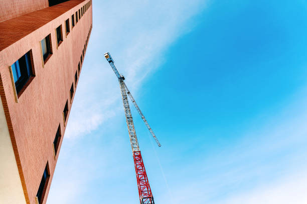 istock A construction crane next to a finished building, with blue background and negative space for text. 1712995291