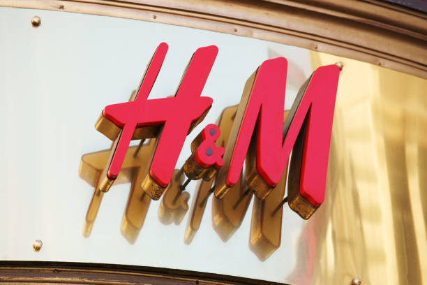 H&amp;M logo on gold background "Vienna, Austria - April 30, 2012: H+M logo on gold background above store entrance. Hennes + Mauritz known as H+M is a Swedish clothing company with stores worldwide." h and m stock pictures, royalty-free photos & images