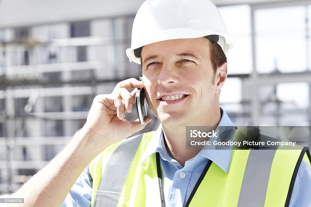 Just touching base with the office A young engineer talking on the phone while at a construction site Adult Stock Photo