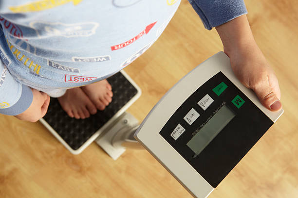 молодой мальчик, стоя на цифровые весы укороченные - emaciated weight scale dieting overweight стоковые фото и изображения