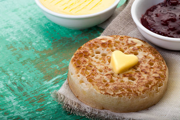 Heart shaped butter on toasted crumpet Melting butter on a crumpet with jam and butter in the background Crumpet with Butter stock pictures, royalty-free photos & images