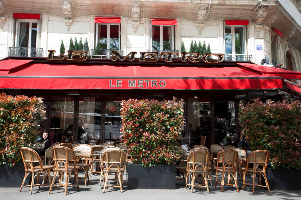 Paris, France - April 01, 2006 : A lady passes the busy terrace in front of a bar cafe on the corner of a street in the 1st arrondisement