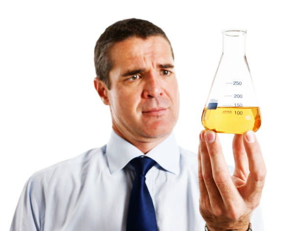 istock Mature man looks seriously at yellow fluid in lab flask 171302036