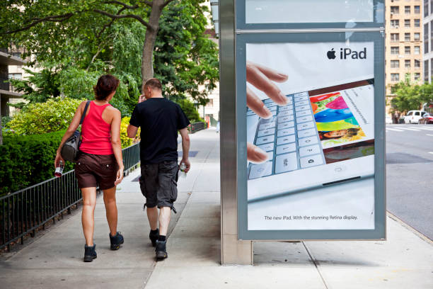 New York City "New York City, USA - June 8, 2012: Young couple passing a bus shelter with advertising of the new iPad with the Retina display on West End Avenue." bus shelter stock pictures, royalty-free photos & images