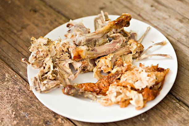 Chicken Bones A high angle close upshot  of a plate full of leftover skin and bones after a rotisserie chicken has been striped of its meat. The leftovers can  be used to make chicken stock. animal bone stock pictures, royalty-free photos & images