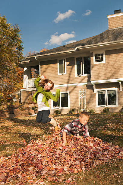istock Children Playing in the Fall Leaves Pile by Their Home 171303290
