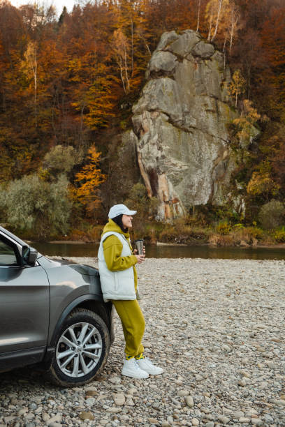 istock woman standing near car drinking tea looking at mountain river 1713034948