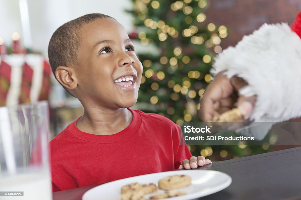 Poco niño sonriendo en Santa comer galletas de Navidad - Foto de stock de Navidad libre de derechos