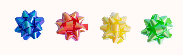 Bright red, yellow, blue and green paper ball bows on a white background. Top view.