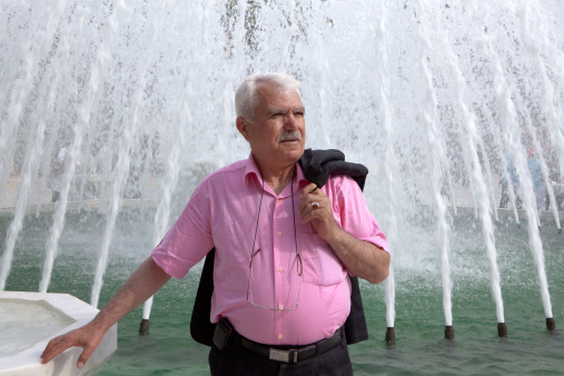 Turkish Man in front of a Fountain and holding his jacket,