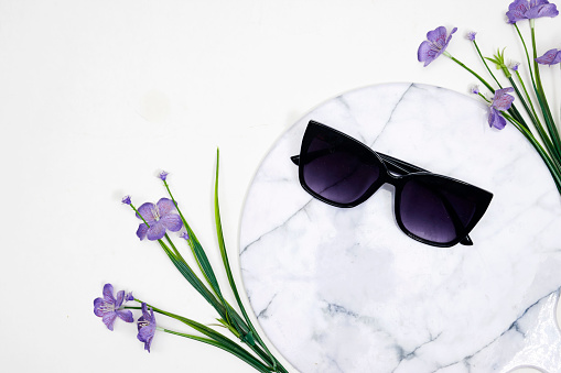 summer sunglasses on marble board or podium with genarium flowers