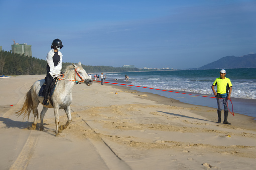 Hainan, China Jan 19, 2019 riders riding on a horse on the beach close to the sea