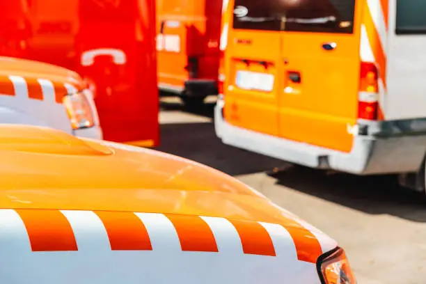 Detail of a fire and emergency vehicle, with the unfocused background of a fire engine parking lot.