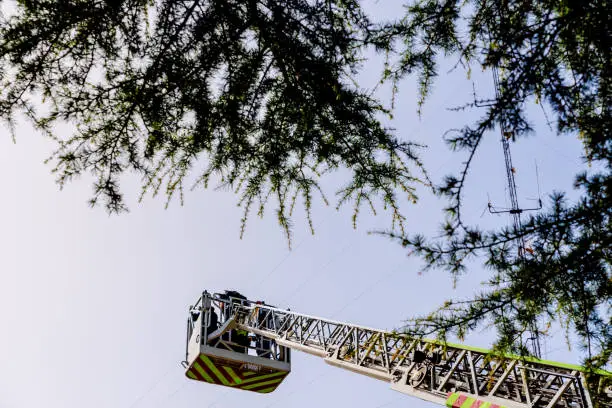 Mechanical ladder of firefighters seen from below with blue sky in the background.