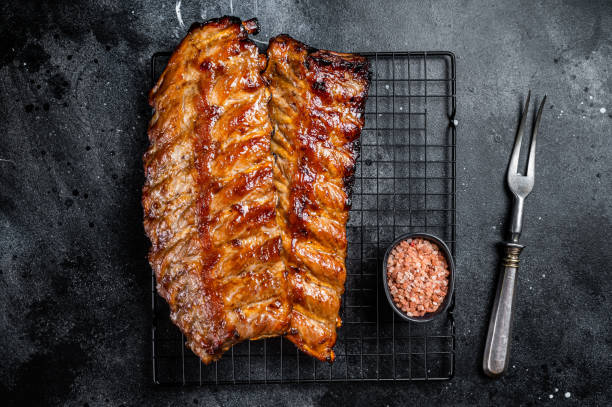 istock BBQ grilled pork spare ribs on a rack. Black background. Top view 1713046319