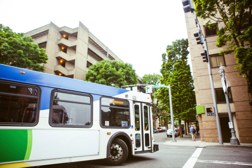 A bus takes a hard corner through an intersection in downtown Portland Oregon.  SOME MOTION BLUR; focus on the bus.  Horizontal image.