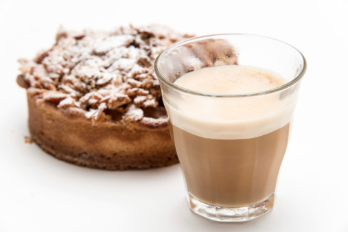 Cortadito (small expresso coffee latte) and a piece of cake on white background