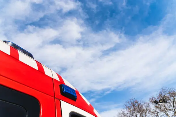 Red roof of a medicalized ambulance over blue sky with clouds and copy space, to care for pandemic sufferers.