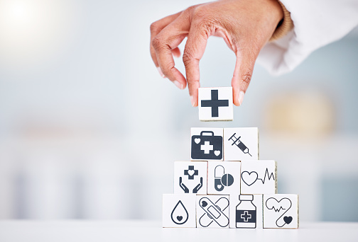 Hands, healthcare and a building blocks tower in a hospital with a doctor closeup for health insurance. Medicine, icon and symbol with a medicine professional in a clinic for cardiology or treatment