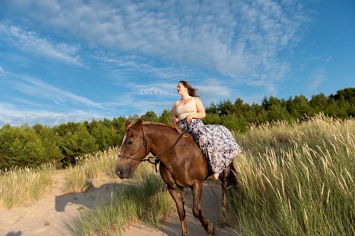 A female riding a horse in a green field on a blustery day
