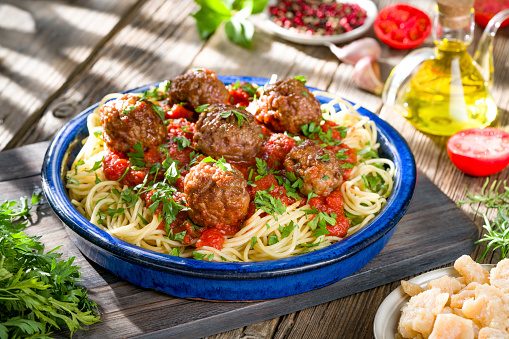 Spaghetti with meat balls and tomato sauce homemade over rustic wooden table board with ingredients, italian food