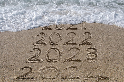 New year 2024 written on sandy beach with waves