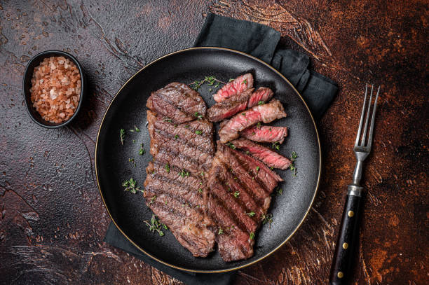 istock Barbecue denver strip beef meat steak on a plate. Dark background. Top view 1713060544