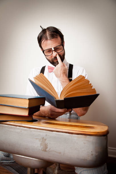 istock Nerdy Guy Sitting at Desk Reading And Picking His Nose 171306131